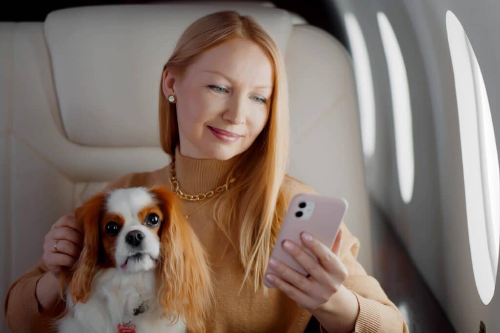 Woman Holding A Phone And Her Pet Dog In A Charter Flight