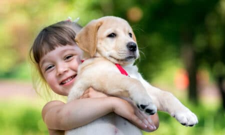 Little Girl Hugging Her Puppy Dog