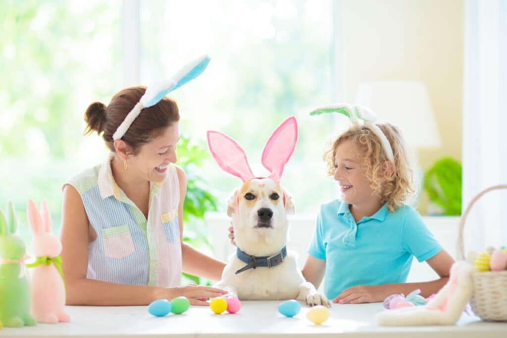 Mother And Child Color Easter Eggs With Their Dog With Bunny Ears