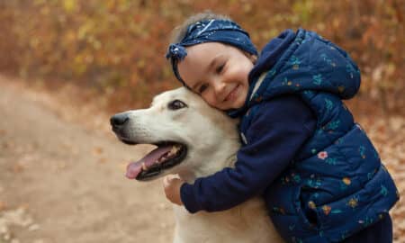 Little Girl Hugging Dog During A Walk In The Woods